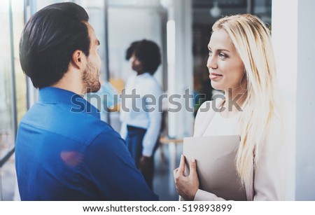 Two coworkers discussing business strategy in modern office.Successful confident hispanic businessman talking with blonde woman. Horizontal, blurred background