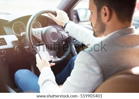 Businessman texting on his mobile phone while driving. Dangerous driver. Royalty-Free Stock Photo #519905401
