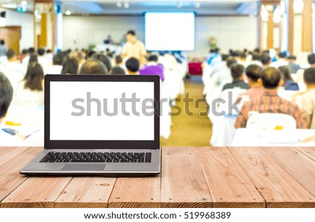 Computer on the table, blur image of inside conference room as background.