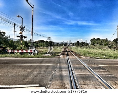 Perspective view of Thailand Countryside a rail crossing barrier with Thai alphabet meaning to beware the crossing point