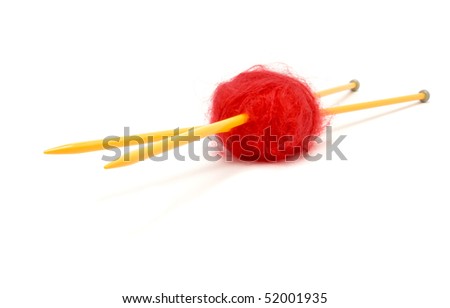 A small ball of red mohair wool pierced with large yellow knitting needles against white.