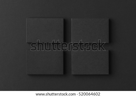 Mockup of four black business cards stacks arranged in rows at black paper background.