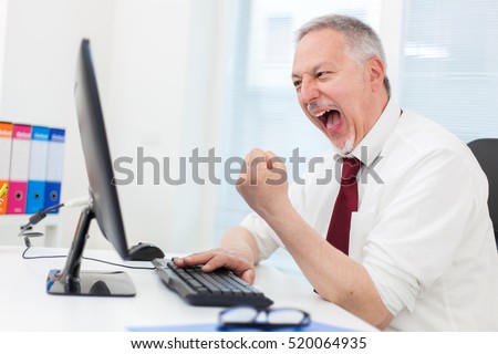 Very happy businessman looking at his computer monitor Royalty-Free Stock Photo #520064935