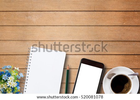 Blank notebook, smart phone and coffee cup on wooden table top view with copy space.Office supplies and gadgets on desk table.