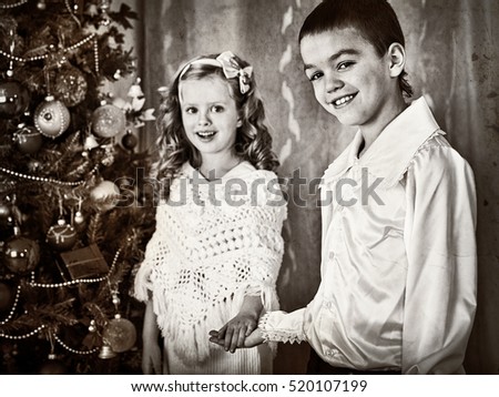 Black and white picture children under Christmas tree. Christmas retro style. Old picture. Brother and sister meet Christmas.