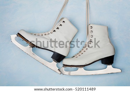 Vintage ice skates for figure skating hanging on the background of blue wall.