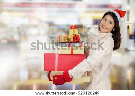 Shopping concept. Asian woman holding a lot of gift boxes over shopping center background. Christmas, New year, Holidays, Celebration and people with happy time.