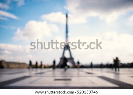OUT OF FOCUS: People in front of Eiffel Tower against blue cloudy sky. Paris, France. 