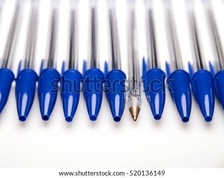 Blue ballpoint pens capped with one uncapped on white background Royalty-Free Stock Photo #520136149