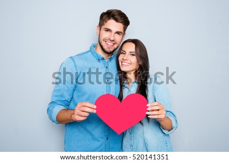 Young happy couple in love holding red paper heart.
