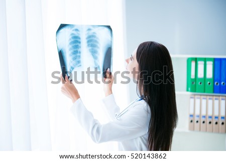 Female doctor looking at X-rays picture of patient's lung.