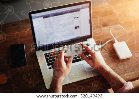Rear view of male hands holding call business card before put contact information on laptop keyboard. Soft focus on the hands, Infographics effect of networking connection everywhere