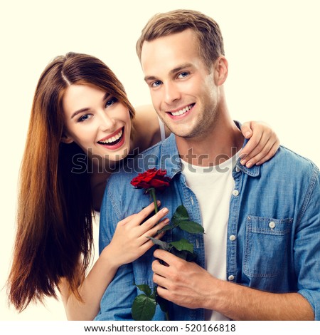 Portrait of young happy hugging couple with rose, close to each other, with smile. Caucasian models in love, relationship, dating, flirting, lovers, romantic concept.
