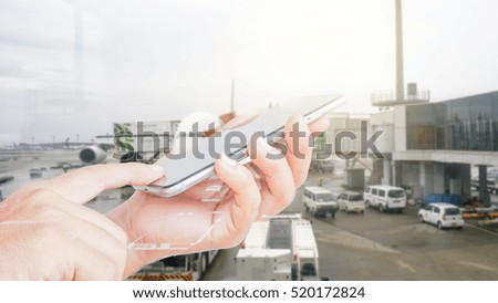 Double exposure of hand hold and touch screen smartphone with airport blurry background. 