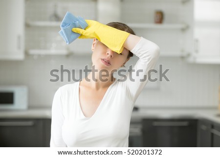Tired and exhausted woman, frustrated with doing much work about the house resting for a minute or wiping her forehead after finishing work. Home, housekeeping concept  Royalty-Free Stock Photo #520201372