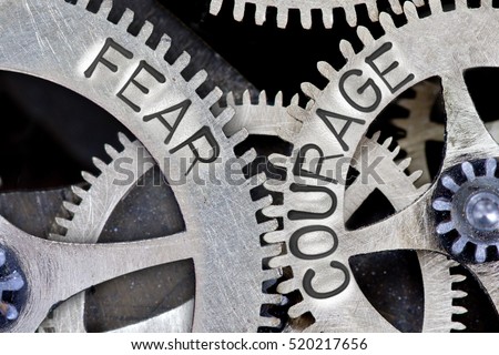Macro photo of tooth wheel mechanism with arrows and FEAR, COURAGE letters