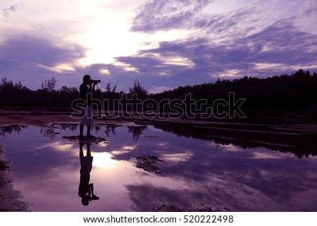 Mirror of purple sky in the morning reflection to the water with shadow of photographer in Thailand.

