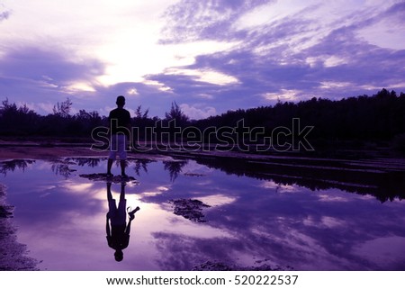 Mirror of purple sky in the morning reflection to the water with shadow of photographer in Thailand.

