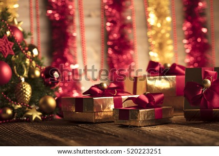 Golden presents with red ribbon under christmas tree. Wooden background and table. Red and gold. Place for typography and logo. Copy space.