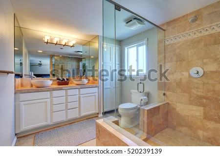 Master bathroom interior with walk in shower and white vanity cabinet with two bowl sinks. Northwest, USA