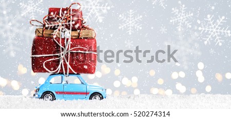 Blue retro toy car delivering Christmas or New Year gifts on festive gray background Royalty-Free Stock Photo #520274314