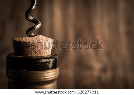 Bottle of wine with corkscrew on wooden background Royalty-Free Stock Photo #520277911