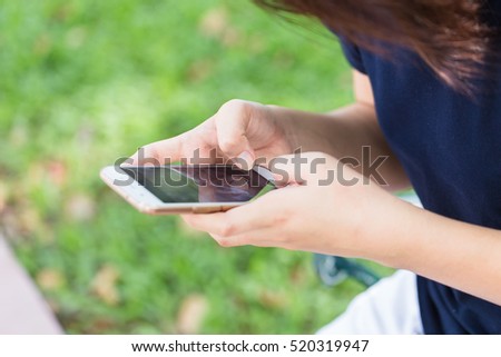 teen phone chat, Asian girl black short hair using or play with her touch screen smartphone in the park.