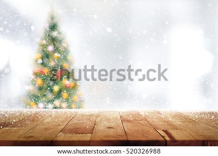 Wood table top on blur Christmas tree  in snowfall background - can be used for display or montage your products