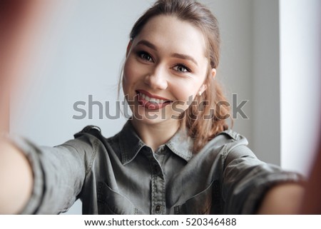 Woman in shirt making selfie. gray background
