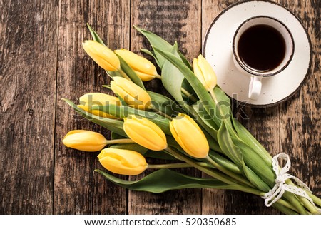 Coffee mug with yellow tulip flowers and notes good morning on blue rustic table from above, breakfast on Mothers  or Women day