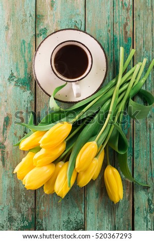 Coffee mug with yellow tulip flowers and notes good morning on blue rustic table from above, breakfast on Mothers  or Women day