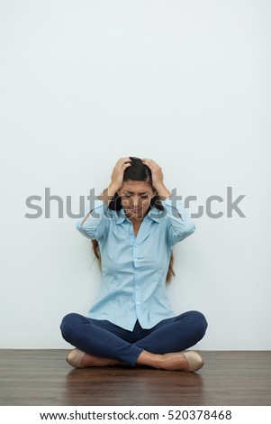 Upset Woman Sitting on Floor and Clutching Head