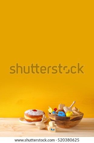 Image of jewish holiday Hanukkah with wooden dreidels colection (spinning top) and donut on the table