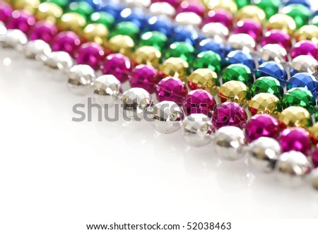 rows of colorful mardi gras beads strung out in a line with reflection on white background