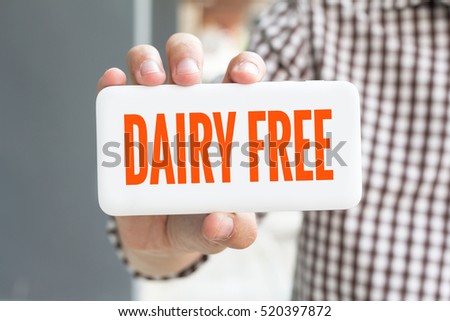 Man hand showing DAIRY FREE word phone with  blur business man wearing plaid shirt. Royalty-Free Stock Photo #520397872