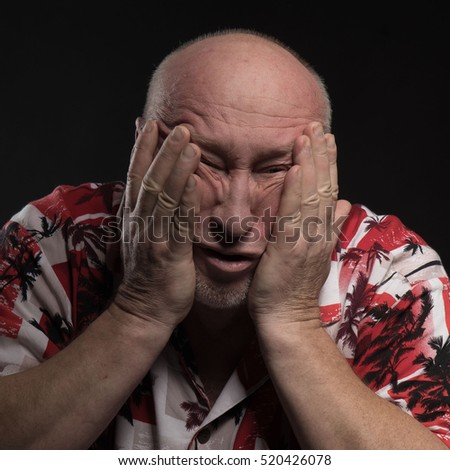 emotional portrait of a bald man with large hands on a black background