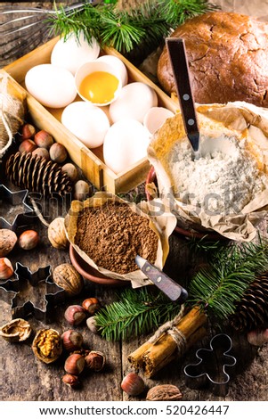 Christmas or New Year baking cake background. Dough, dough ingredients - flour, chocolate, walnuts, hazelnuts, sugar eggs cinnamon and Christmas decorations on wooden rustic background