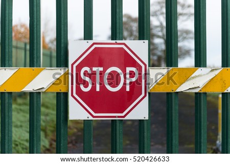 Stop sign on secure metal gate barrier background