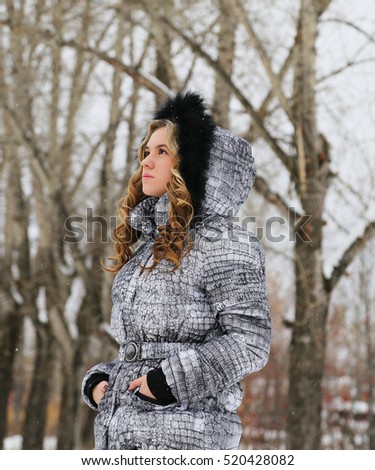 Beautiful laughing blonde in the winter down jacket with fur hood