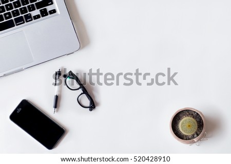 White office desk table with laptop, cactus, smartphone, and glass. Top view with copy space, flat lay.