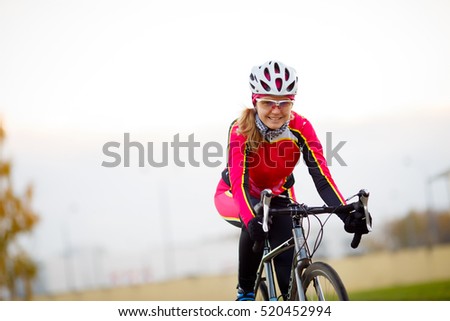 Happy sporty woman in sports protective clothing riding bicycle