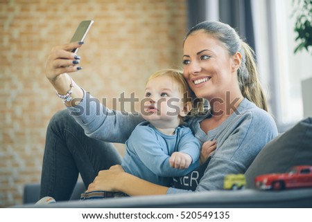 Mom and toddler taking selfie in cosy living room
