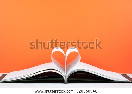 Old open hardback book, page decorate into a heart shape for love in Valentine's day with red pink color background and vintage tone style. Composition of love with open book heart. Romantic reading Royalty-Free Stock Photo #520560940