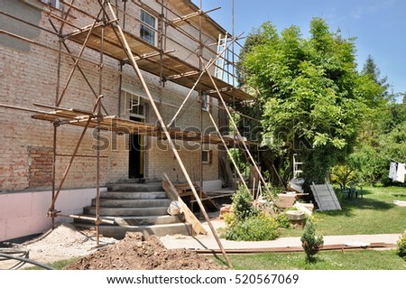 detail renovation of house with scaffold and nice garden with tree and blue sky. Reconstruction of building