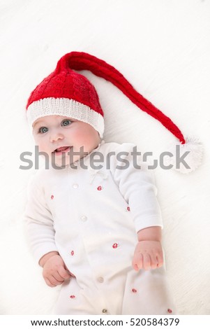 The little girl lies on a floor in studio in Santa Claus's cap