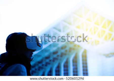VR virtual reality - Woman wearing a virtual reality headset, controlling the experience with hand gesture - looking at green virtual background