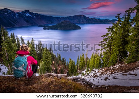 Backpacker Girl Looking at Crater Lake at Sunset Wizar Island and Watchman Peak in the Background Royalty-Free Stock Photo #520690702