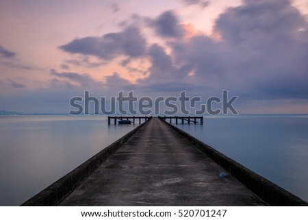 Perspective view of a cement pier on the sea at sunset with perfectly specular reflection