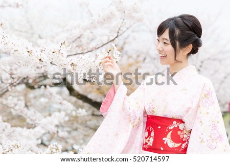 attractive asian woman wearing kimono looking cherry blossoms