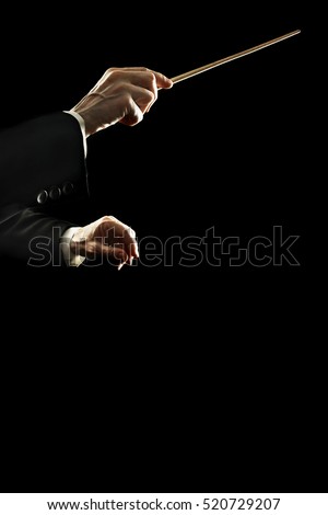 Orchestra conductor music conducting. Conductors hands with baton stick isolated on black background Royalty-Free Stock Photo #520729207